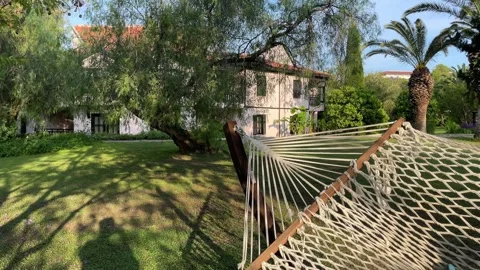 Wicker white hammock is tied between two trees in beautiful garden. Tropical 스톡 동영상 242853021