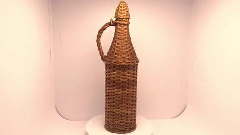 Wicker‑covered bottle rotating on turntable Stock Footage 337243077