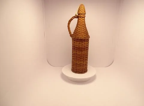 Wicker‑covered bottle on white background Fotos Stock
