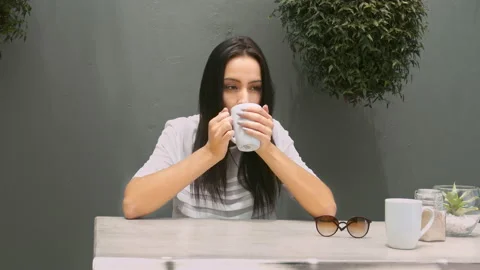 Wide 4k video of a young, beautiful, Latin Hispanic woman drinking coffee in gar Видео 201094133