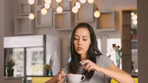 Wide 4k video of a young, beautiful, Latin Hispanic woman drinking coffee in caf Vídeo Stock 201094867