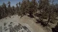 wide aerial ascending up over pine trees near antenna farm HD Footage