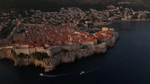 Wide Aerial Drone Pull Back Tilt Up Boats to Dubrovnik Walled Old City Sunset 4K Stock Footage 337850156
