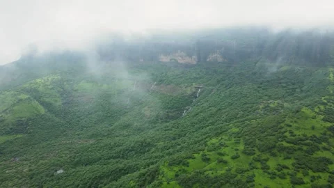 Wide aerial high-angle, long drone shot reveals lush, green mountainside sh.. Video stock 306120005