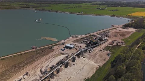 Wide aerial orbit of active sand quarry and processing plant beside a lake 库存影片 332613400
