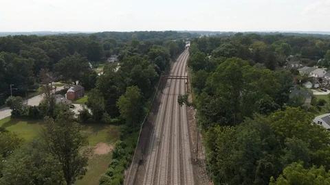Wide aerial pull away over main line Philadelphia train tracks in Berwyn, PA Stock Footage 118978664