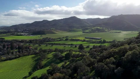 Wide aerial pullback revealing rolling hills and vineyards, gliding back from Stock Footage 330918916