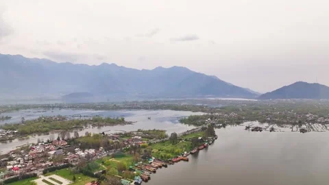 Wide aerial pullback revealing Srinagar city, Dal Lake, and Himalayan mountains. Видео 333793014