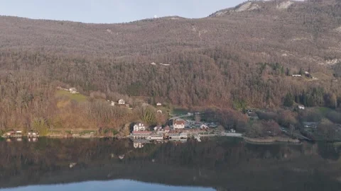 A wide aerial shot captures the tranquil village of Aiguebelette-le-Lac nestled Stock Footage 346671994