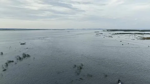 Wide aerial view of calm river water and low marsh islands beneath a pale c.. Stock Footage 344054355