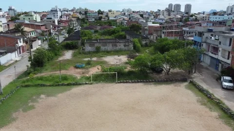 Wide aerial view of a hillside favela with a community sports field. Stock Footage 327624063