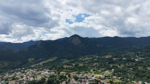 Wide aerial view of a massive rock cliff and mountain peak surrounded by forest  動画素材 341740472