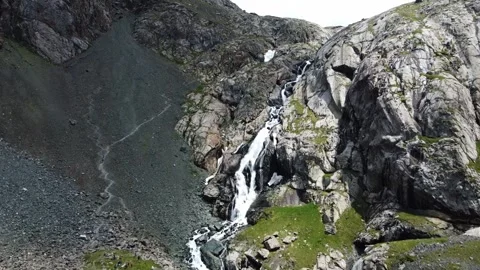 Wide aerial view of multi-tiered mountain waterfall cascading in rocky gorge Stock Footage 335079403