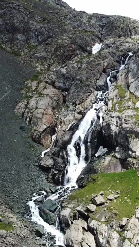 Wide aerial view of multi-tiered mountain waterfall cascading through gorge Stock Footage 336686812
