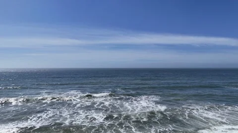 Wide Aerial View of Ocean Waves Crashing Under a Clear Blue Sky Video stock 331976840