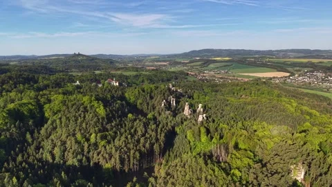 Wide aerial view of pine forest and jagged rock spires rising above patchwork Stock Footage 346262889