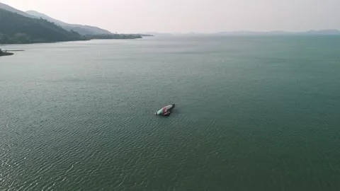 Wide angle aerial orbit of isolated sunken boat in calm bay with misty tropical Stock Footage 320429361