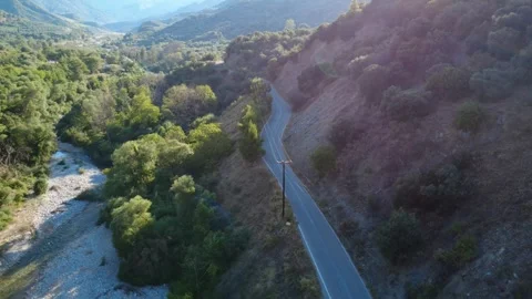 Wide angle aerial view of a mountain highway curve beside a forest river Stock Footage 343962224
