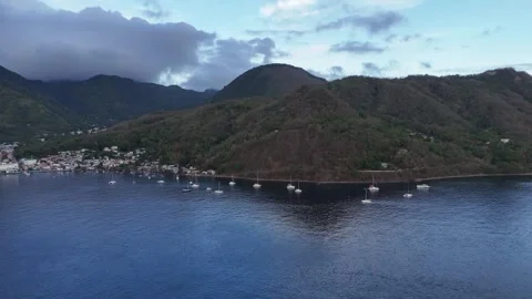 Wide angle aerial view of a secluded tropical bay surrounded by dark volcanic Stock Footage 338111189