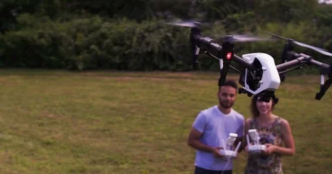 Wide angle aerial of young couple flying a drone in the park. Stock Footage 80300174
