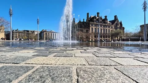 Wide-angle cinematic view of large water fountain jet and Bradford City Hall Stock Footage 334995605