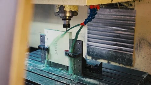 Wide angle of CNC milling machine cutting material with green coolant in factory Stock Footage 341569431