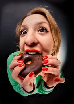 Wide-angle distortion perspective portrait of a girl who bites a donut in cho Stock Photos