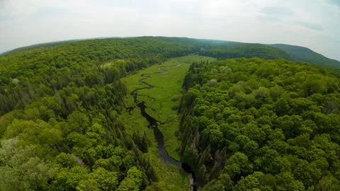 Wide angle drone perspective tracking a winding river through wetland fields Foto stock