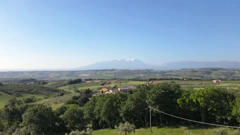 Wide angle drone shot going over olive trees and a small village moving Stock Footage 234478492
