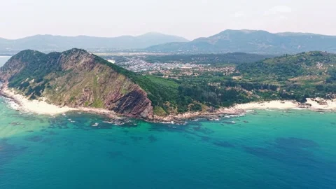 Wide angle drone tracking past sea cliff beach with distant village 4K Stock Footage 340069353