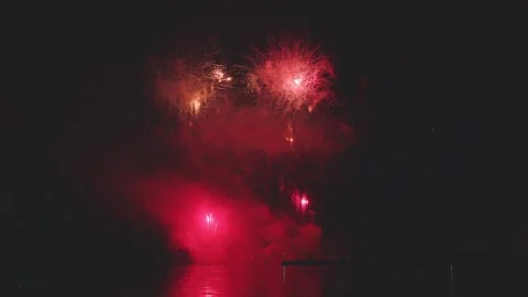 Wide angle fireworks display reflecting vividly on ocean water surface Video stock 340632847