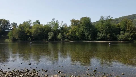 Wide angle footage on two man waist deep in water fly fishing under blue sky Stock Footage 263059296