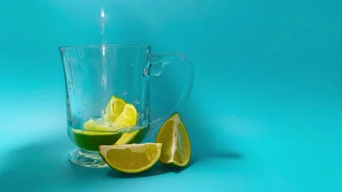 Wide angle front view of pouring water in a glass cup mug with juicy green .. Video stock 318127636