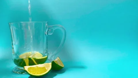 Wide angle front view of pouring water in a glass cup mug with juicy green .. 動画素材 318128185