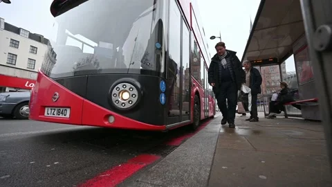 WIDE ANGLE ground level shot as a man waves for a Red London Double Decker Bu Video stock 134613555