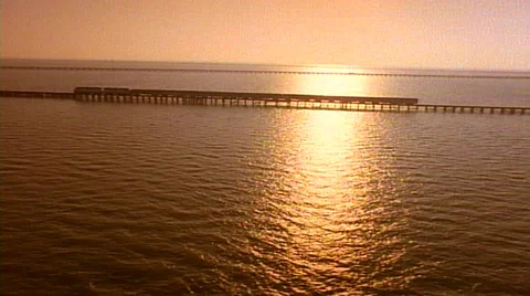 Wide angle - helicopter shot of train over bridge moving right to left at sunset Stock Footage 29803890