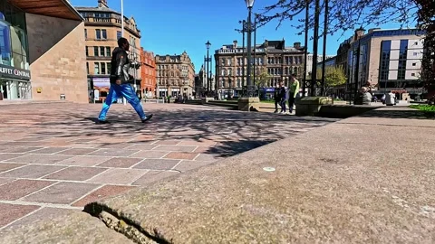 Wide-angle low-angle view of people walking in Bradford city square Видео 334995713