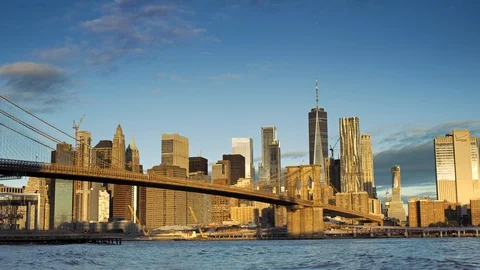 Wide angle of Manhattan skyline lit by rising sun and reflecting into East River Stock Footage