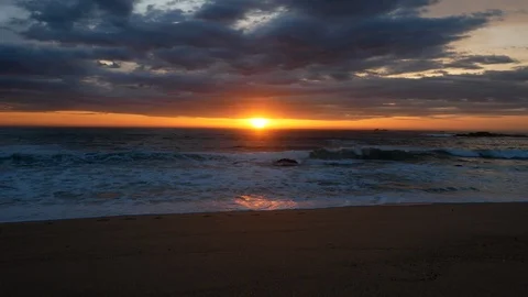 Wide angle over sandy beach at sunset with vivid red / orange sky Stock Footage 106648323