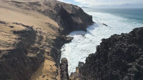 Wide angle pan over rugged coastal cliffs and crashing ocean waves 스톡 동영상 331195179