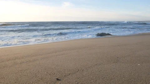 Wide angle pan up on sandy beach to ocean waves crashing on shoreline Stock Footage 103279001
