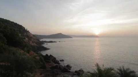 Wide angle panning shot of ocean, palm trees and mountain at sunrise in India Stock Footage 33569151