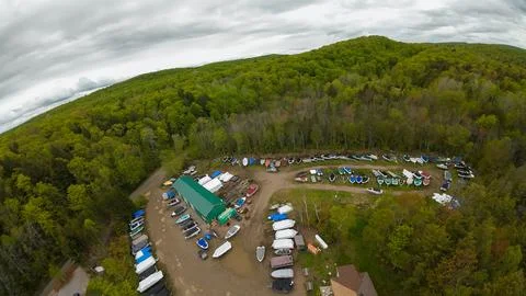 Wide angle panoramic drone shot of a boat storage yard enclosed by forests 스톡 사진