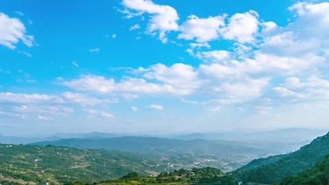 Wide angle panoramic view of lush green mountain ranges under a bright blue sky 動画素材 341960640