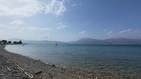 Wide angle pebble beach with distant kitesurfers on Greek island Video stock 337046372