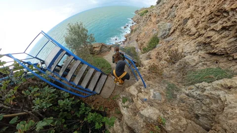 A wide-angle perspective of a man and a woman descending a vibrant blue Stock Footage 294462465