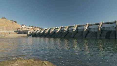 Wide angle perspective of Nimbus Dam along the American River bank Vídeos de archivo 348036506