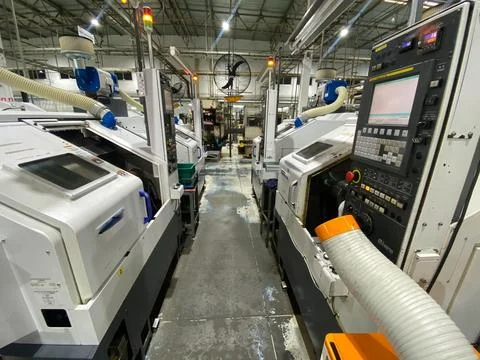Wide-angle photograph of multiple CNC lathe machines arranged along a product Stock Photos
