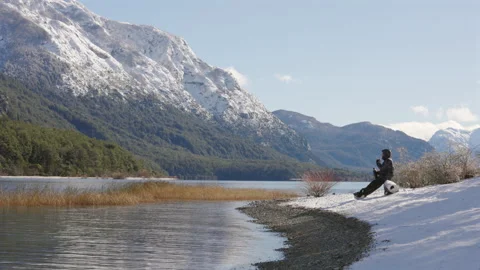 Wide angle scenic view of man drinking Mate by sunny winter lake in Patagonia Stock Footage 327443713