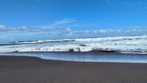 A wide-angle shot captures powerful ocean waves breaking over dark volcanic.. Video stock 331179419